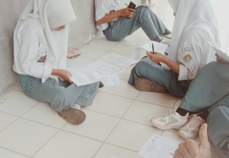 Foto Peserta didik mengikuti ujian duduk di lantai luar ruangan kelas, 